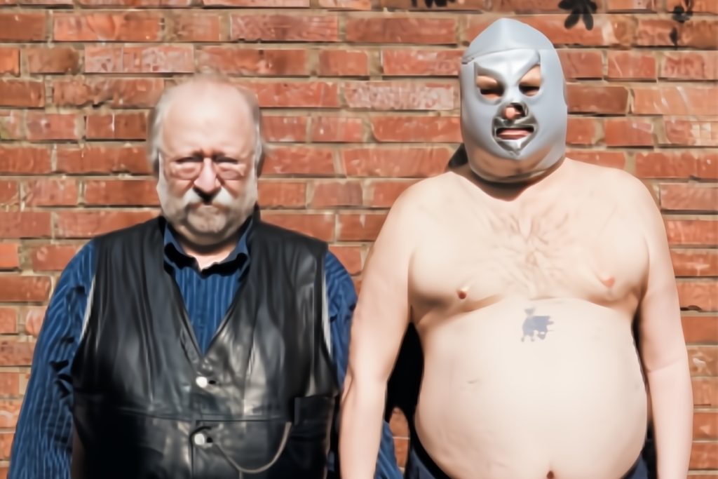 Johannes van Dam and the Undercover Glutton holding hands in front of a brick wall.