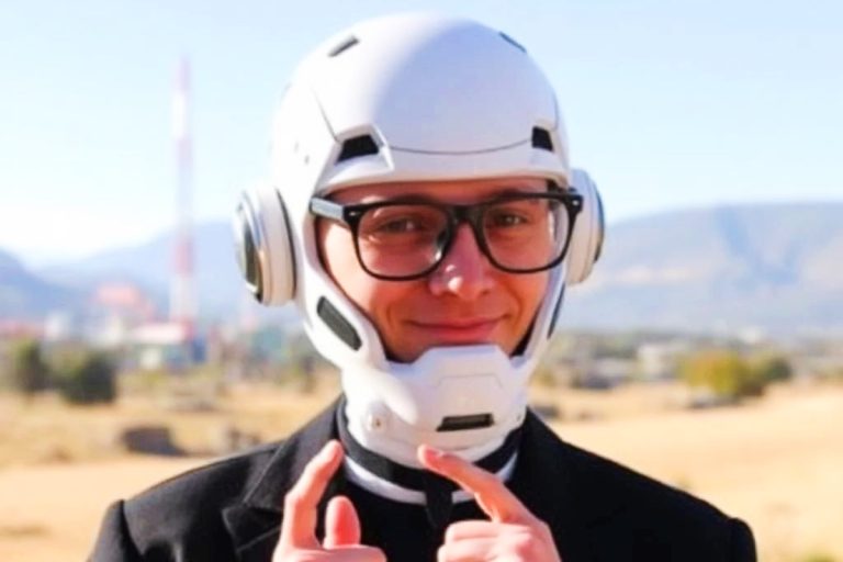 A nerdy boy wearing a Star Wars helmet holds up his fingers to explain something.